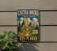 A vintage-style metal sign for Castle Rocks State Park in Idaho, featuring a scenic mountain landscape with pine trees and a winding path.