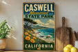 A vintage-style sign for Caswell Memorial State Park in California, featuring a scenic landscape with a beach, mountains, and a pine tree.