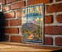 A vintage-style metal sign for Catalina State Park in Arizona, featuring a desert landscape with mountains, cacti, and a trail.
