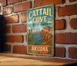 A vintage metal sign for Cattail Cove State Park in Arizona, featuring a scenic illustration of the park's landscape.