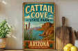A vintage-style metal sign for Cattail Cove State Park in Arizona, featuring a desert landscape with mountains, cacti, and a body of water.