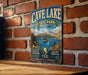 A vintage metal sign for Cave Lake State Park, Nevada, featuring a scenic mountain landscape and water.