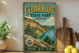 A vintage-style sign for Cedar Bluff State Park in Kansas, featuring a scenic landscape with a river and mountains.