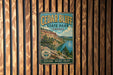 A vintage metal sign for Cedar Bluff State Park in Kansas, featuring a scenic landscape with a lake and mountains.