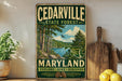 A vintage-style metal sign for the Cedarville State Forest in Maryland, featuring a scenic landscape with trees, a lake, and mountains.
