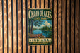 A vintage metal sign for Chain O Lakes State Park in Indiana, featuring a scenic image of a lake with a canoe, is displayed on a wooden wall.