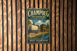 A vintage metal sign for the Champoeg State Heritage Area in Oregon, featuring a wagon train and a sign that says "Established 1843" and "Where Oregon Began".