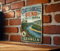 A vintage metal sign for Chattanooga Bend State Park in Georgia, featuring a scenic landscape with a river and mountains.
