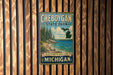 A vintage-style metal sign for Cheboygan State Park, featuring a scenic landscape with pine trees, a lake, and mountains.
