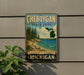 A vintage-style sign for Cheboygan State Park, featuring a scenic image of a lake surrounded by pine trees and mountains.