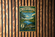 A vintage-style metal sign for Cheesecake State Park in New Jersey, featuring a scenic landscape with a river and trees.