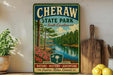 A vintage-style metal sign for Cheraw State Park in South Carolina, featuring a scenic image of a lake surrounded by pine trees and a wooden dock.