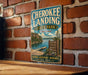 A vintage-style sign for the Cherokee Landing State Park in Oklahoma, featuring a scenic image of the park's natural surroundings and a wooden dock.