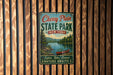 A vintage-style metal sign for Cherry Plain State Park in New York, featuring a scenic image of a lake and mountains with a canoe.