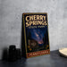 A vintage-style sign for Cherry Springs State Park in Pennsylvania, featuring a night sky scene with pine trees and a starry sky.