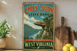 A vintage-style sign for Chief Logan State Park in West Virginia, featuring a scenic landscape with a cliff overlooking a river.