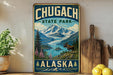 A vintage-style metal sign for Chugach State Park in Alaska, featuring a scenic mountain landscape with a moose in the foreground.