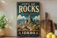 A vintage-style sign for the City of Rocks National Reserve in Idaho, featuring a scenic mountain landscape.