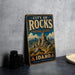A vintage-style sign for the City of Rocks National Reserve in Idaho, featuring a mountainous landscape with a prominent rock formation.