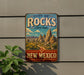 A vintage-style metal sign for City of Rocks State Park in New Mexico, featuring a desert landscape with mountains and a prominent "New Mexico" text.