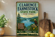 A vintage-style metal sign for Clarence Fahnestock State Park in New York, featuring a scenic landscape with a lake, mountains, and an eagle.