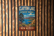 A vintage metal sign for Clayton Lake State Park in New Mexico, featuring a scenic landscape with mountains, a lake, and a desert.
