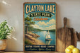 A vintage-style sign for Clayton Lake State Park in Oklahoma, featuring a sailboat on a lake and a scenic landscape.