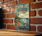 A vintage-style metal sign for Clayton Lake State Park in Oklahoma, featuring a sailboat on a lake and text promoting various outdoor activities such as boating, fishing, hiking, camping, and relaxation.
