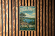 A vintage metal sign for the Cockset State Forest in Connecticut, featuring a scenic landscape with a lake and pine trees.