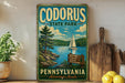 A vintage-style sign for Codorus State Park in Pennsylvania, featuring a scenic illustration of a lake, pine trees, and a sailboat.