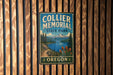 A vintage metal sign for Collier Memorial State Park in Oregon, featuring a scenic landscape with mountains, a lake, and pine trees.