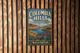 A vintage metal sign for Columbia Hills State Park in Washington, featuring a scenic landscape with mountains, a lake, and sunflowers.