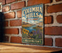 A vintage-style metal sign for Columbia Hills State Park in Washington, featuring a scenic landscape with mountains, water, and flowers.