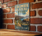 A vintage-style metal sign for Columbia Plateau Trail, located in Washington State Park, is displayed on a brick wall.
