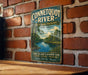 A vintage-style metal sign for the Connecticut River State Park Preserve in New York, featuring a scenic image of the river surrounded by lush greenery.
