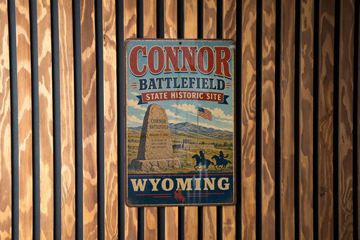 A vintage metal sign for the "Connor Battlefield State Historic Site" in Wyoming, featuring a monument and a horse-drawn carriage.