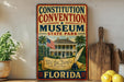 a vintage-style sign for the Constitution Convention Museum in Florida, with a large American flag and a house illustration.