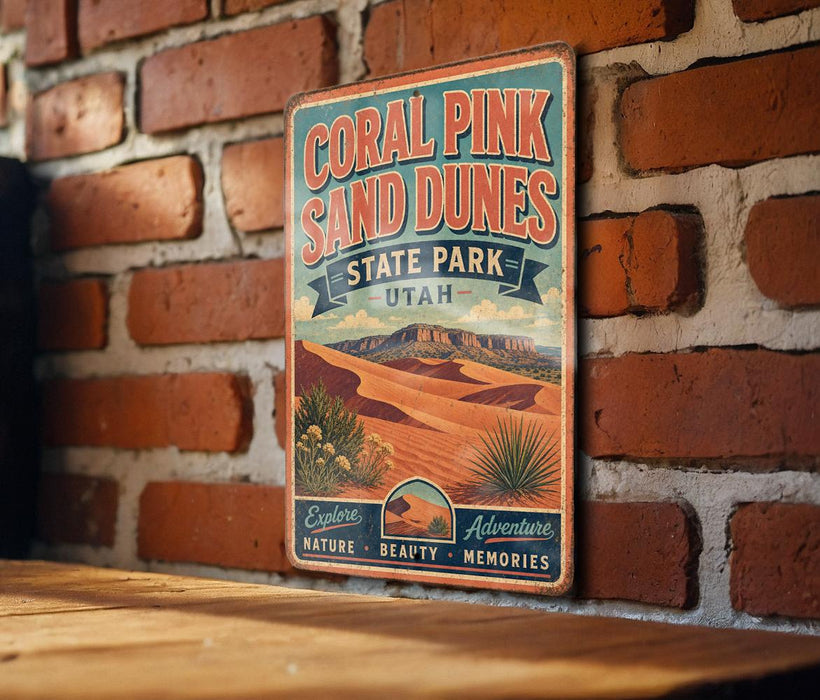 A vintage-style metal sign for the Coral Pink Sand Dunes State Park in Utah, featuring a desert landscape with mountains and desert plants.