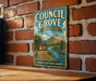 A vintage-style metal sign for Council Grove State Park in Montana, featuring a scenic landscape with mountains, trees, and a river.