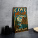 A vintage metal sign for Cove Palisades State Park in Oregon, featuring a scenic landscape with a lake and mountains.