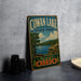 a vintage metal sign for Cowan Lake State Park, with a scenic illustration of the lake and surrounding landscape.