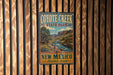A vintage-style metal sign for Coyote Creek State Park in New Mexico, featuring a scenic landscape with a river and mountains.