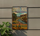 A vintage-style metal sign for Coyote Creek State Park in New Mexico, featuring a scenic landscape with mountains, a river, and a tree.