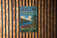 A vintage metal sign for Craig Lake State Park in Michigan, featuring a scenic illustration of a lake with a canoe and pine trees.