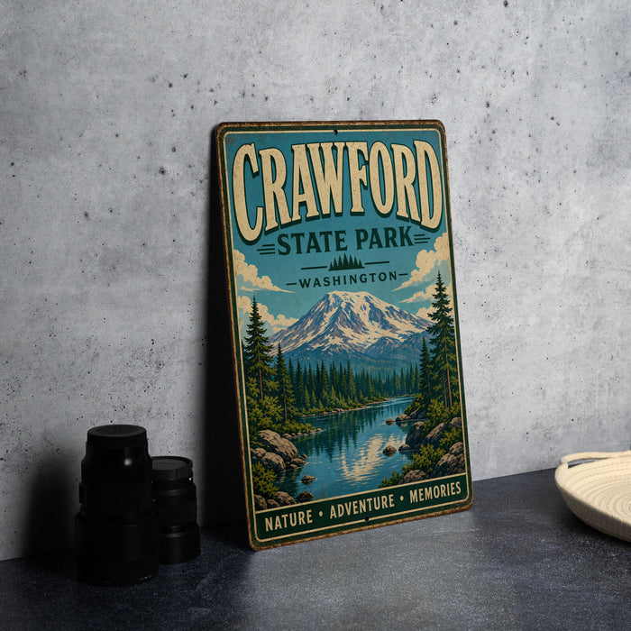 A vintage metal sign for Crawford State Park in Washington, featuring a scenic mountain landscape with a river and pine trees.