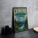 A vintage metal sign for Crawford State Park in Washington, featuring a scenic mountain landscape with a river and pine trees.