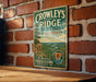 A vintage metal sign for "Crowley's Ridge State Park in Arkansas" is displayed on a brick wall.