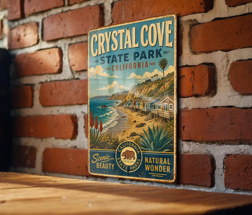 A vintage-style metal sign for Crystal Cove State Park, California, featuring a scenic beach landscape with palm trees and a wooden house.
