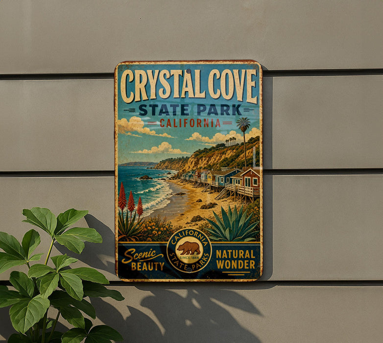 A vintage-style metal sign for Crystal Cove State Park, California, featuring a scenic beach landscape with palm trees and other natural elements.