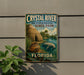 A vintage-style sign for Crystal River Archaeological State Park in Florida, featuring a manatee and a thatched-roof hut in a tropical setting.